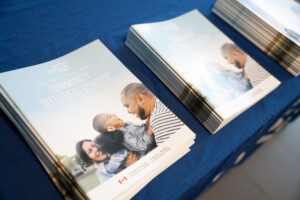 Photo of printed copies of the Community Settlement Strategy in three piles on a blue table