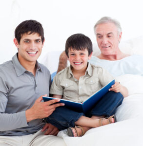 Affectionate father and son visiting grandfather and reading together