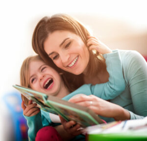 Mother and toddler reading and laughing together while child holds mother's head